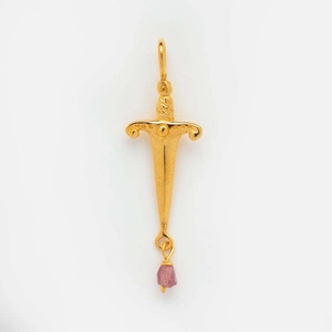 Macro shot of gold sword pendant featuring a vibrant pink zircon stone detail