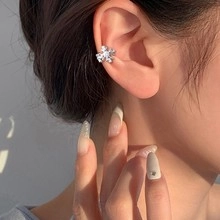 Macro shot of silver flower ear cuff with sparkling zircon stones on a model ear