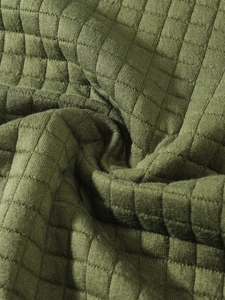 Macro shot of army green quilted fabric detail with textured square grid pattern