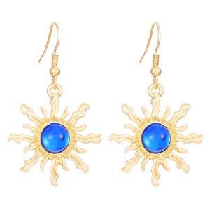 Detail of vintage gold sunburst earrings with a central round blue gemstone inlay