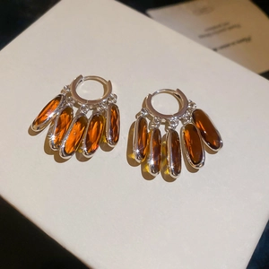 Detail of amber crystal oval fringe drop earrings with polished silver hoops on white box