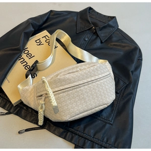Detail of beige woven cross body chest bag with wide strap and knotted zipper puller