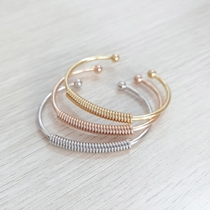 Detailed view of three stainless steel bangles in gold, rose gold and silver finishes