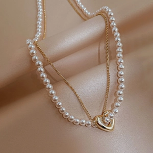 Double-layer gold plated necklace with pearls and heart pendant on champagne silk fabric