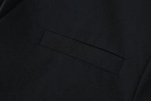 Detailed macro view showing the welt pocket craftsmanship on a black V-neck blazer