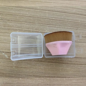 Pink handle foundation brush with brown bristles in an open transparent storage case