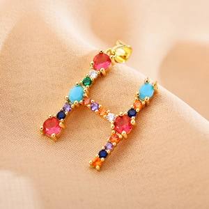 Close-up of golden letter H pendant set with vibrant multi-colored zircon gemstones