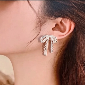 Elegant silver bow earrings with tassel rhinestones worn by a model in a close-up shot