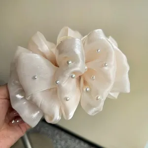 Dettaglio di un fermaglio per capelli a fiocco in organza perlata crema con perle