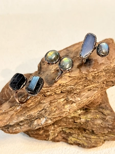 Macro shot of vintage raw tourmaline and labradorite rings on natural bark