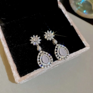 Gros plan détaillé des boucles d'oreilles goutte en zircon rose avec monture florale en argent
