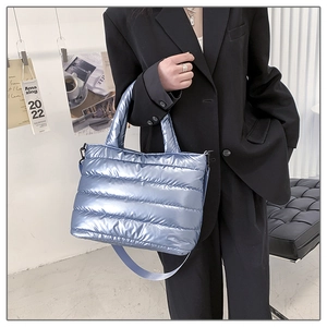 Detail of light blue quilted space cotton shoulder bag with metallic finish on model
