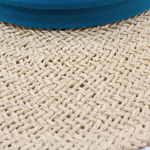 Macro view of blue fabric trim and natural straw weaving on a summer sun hat