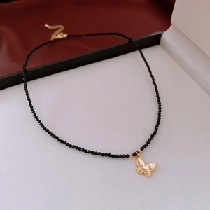 Detail of 18K gold-plated butterfly pendant on a faceted black beaded chain necklace