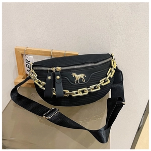 Detail of woven black chest bag with gold chain decoration and metal horse emblem