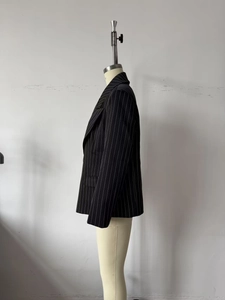 Side view of a black pinstripe blazer for women featuring a minimalist tailored fit