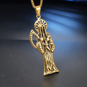 Detailed close-up of golden Santa Muerte pendant with scythe and scales on dark background