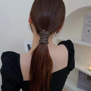 Detail showing deep brown leather hair wrap with gold metal tips on a ponytail hairstyle