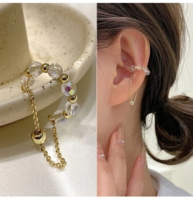 Detail of beaded ear cuff featuring gold metal beads and a transparent faceted chain drop