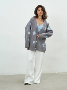 Detail of grey knit cardigan featuring blue flower embroidery and premium texture