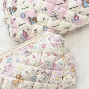Detail of quilted cosmetic pouches featuring cartoon dogs and floral star patterns