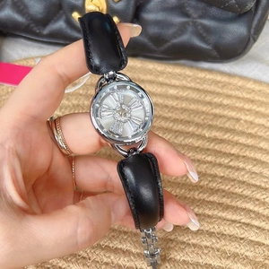 Detail of women's silver watch with rotating crystal dial and black leather strap