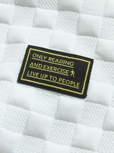 Detail of white waffle knit fabric with contrast black woven label and yellow embroidery