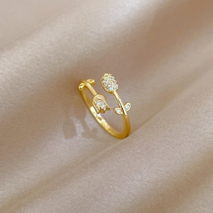Macro detail of tulip-shaped gold ring with white zircons on elegant champagne silk