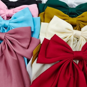 Detailed view of various colorful satin bow hair clips with silky texture and elegant draping