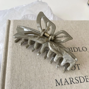 Close-up of a butterfly hair claw clip with grey-green marble texture on a book