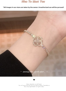 Detail shot of a gold-plated tennis bracelet with a diamond-set clover charm on the wrist