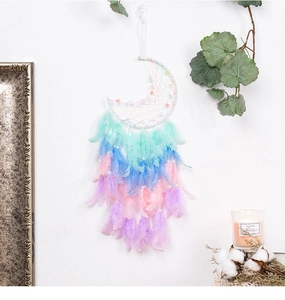Detail of moon dreamcatcher with gradient feathers and pearls on a white wall