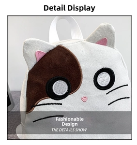 Detail showing the white canvas cat bag with cute ear design and heart-shaped embroidery