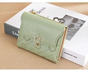 Close-up of light green leather wallet with floral embossing and metal flower detail