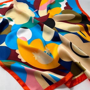 Macro shot of abstract floral silk scarf showing premium satin texture and orange rolled edge