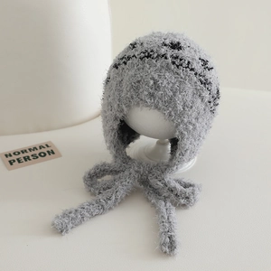 Detail of gray plush earflap hat with black jacquard texture and long straps
