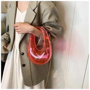 Close-up of pink acrylic box clutch with U-shaped handle and metal chain strap