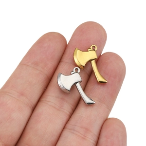 Polished gold and silver stainless steel axe pendants shown on palm for size scale