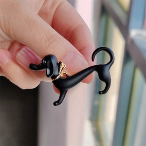 Detailed view of a black dachshund brooch with gold collar and matte texture finish