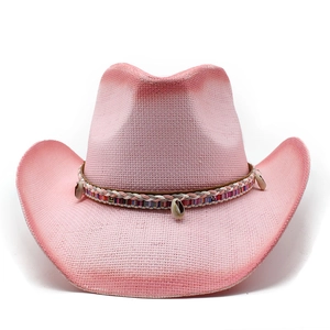 Detailansicht eines rosa Cowboy-Strohhuts mit Ethno-Webband und Muschel-Anhängern