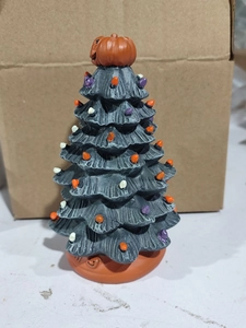 Detail of black Halloween tree with pumpkin topper and colorful mini light bulbs
