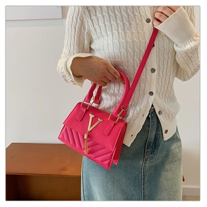 Detail of rose red PU leather handbag with gold V-logo and V-quilted texture