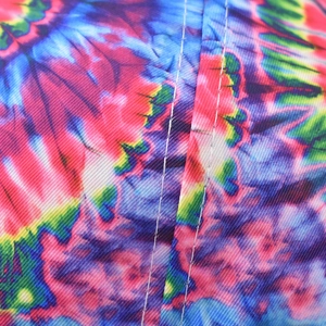 Detailed close-up of vibrant colorful tie-dye patterns on cotton twill baseball cap fabric