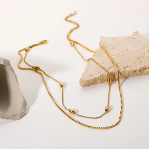 Detail of 18K gold plated double layer necklace with oval beads on textured stones