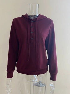 Detalle de sudadera con capucha rojo vino en punto acanalado con cuatro botones frontales