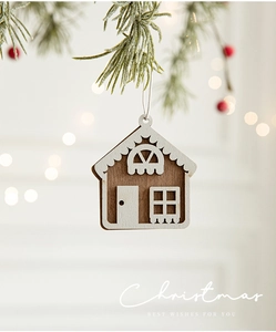 Close-up of wooden house ornament hanging on frosted pine branch with warm bokeh