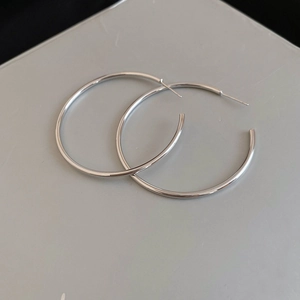 Macro shot of minimalist silver hoop earrings with high-polish finish and slender ear pins