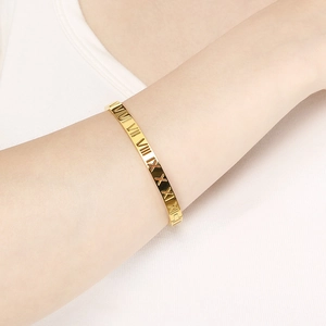 Détail macro du bracelet jonc doré en acier inoxydable avec chiffres romains ajourés