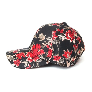 Detailed close-up of intricate red and gold floral embroidery on a black baseball cap fabric