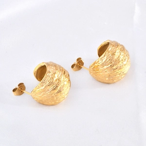 Gold French-style C-shaped earrings with unique brushed lava texture on white fabric